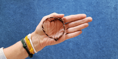 Woman wearing gree, gold and white paracord bracelets, and holding a football patterned paracord bracelet