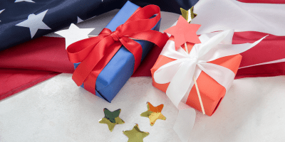 Red and blue wrapped gift packages, with an American flag i the background